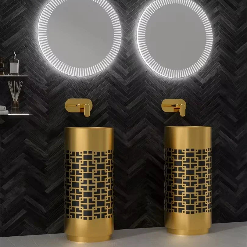 Two gold sinks with geometric patterns against a black chevron-patterned wall.