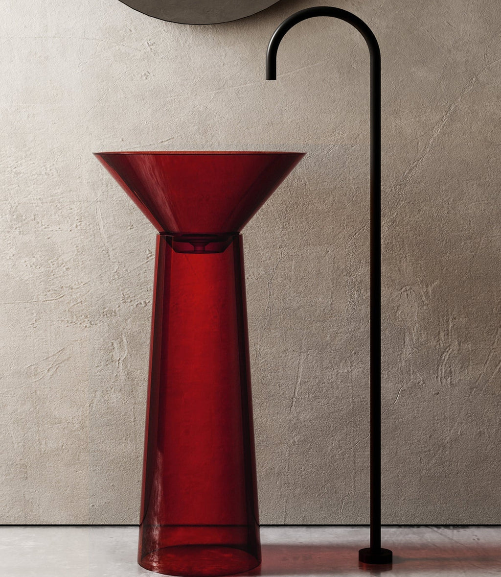 Red glass sink with black faucet against a beige wall