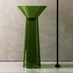 Green freestanding sink with black faucet against a neutral wall.