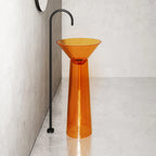 Orange pedestal sink against a neutral wall