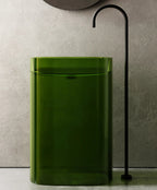 Green rectangular trash can against a neutral wall with a black decorative element.